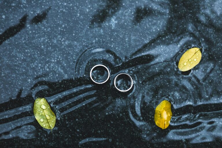 Wedding rings underwater on black background on big yellow leaf